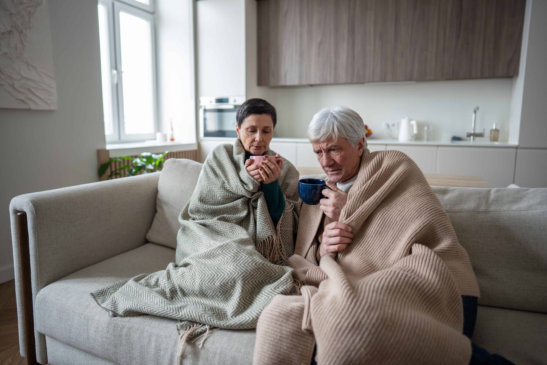 Upset struggling senior couple under blanket